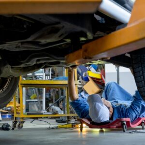 Lower view under car garage worker or technician lie down and check problem