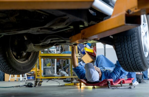 Lower view under car garage worker or technician lie down and check problem